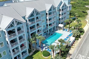 Ein mehrstöckiges Hotel mit Balkonen, einem Swimmingpool und Palmen.