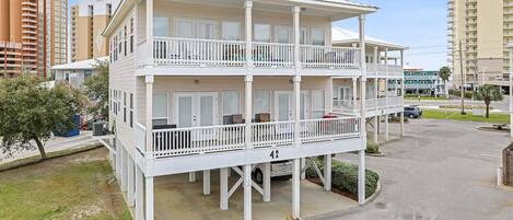 A multi-story hotel with balconies, a parking area, and a view of surrounding buildings.