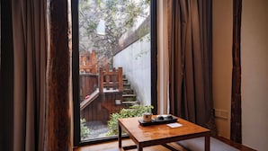 A traditional Japanese room with tatami flooring, a low wooden table with a tray, and a view of a stone staircase leading to a wooden deck. - Sanfuyizhai Homestay (Taizhou)