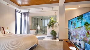 A modern hotel room with a large bed, a television, and a bathroom visible through a glass door. - Sanfuyizhai Homestay (Taizhou)
