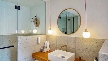 Un baño moderno con una bañera independiente, un espejo grande y un mueble de tocador de madera.