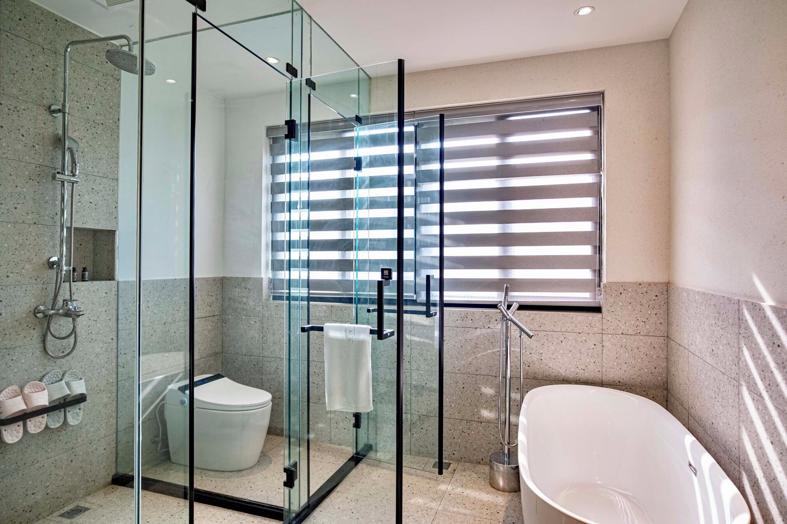 A modern bathroom with a glass-enclosed shower, a toilet, and a bathtub.