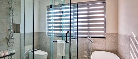A modern bathroom with a glass-enclosed shower, a toilet, and a bathtub.