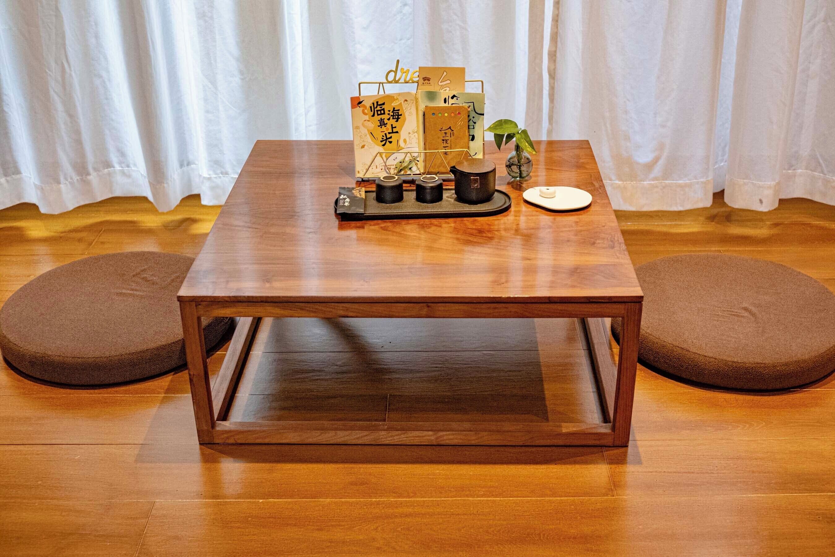 A wooden table with a tray holding a card, a small plant, and a cup.