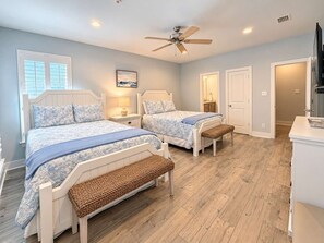 A bedroom with two beds, a ceiling fan, and a wooden floor. - Hammock Dunes Beachside Cottage (Orange Beach)