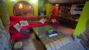 A cozy room with a red sofa, wooden coffee table, and a rustic stone wall. - CASA RURAL INMA (Muñoveros)