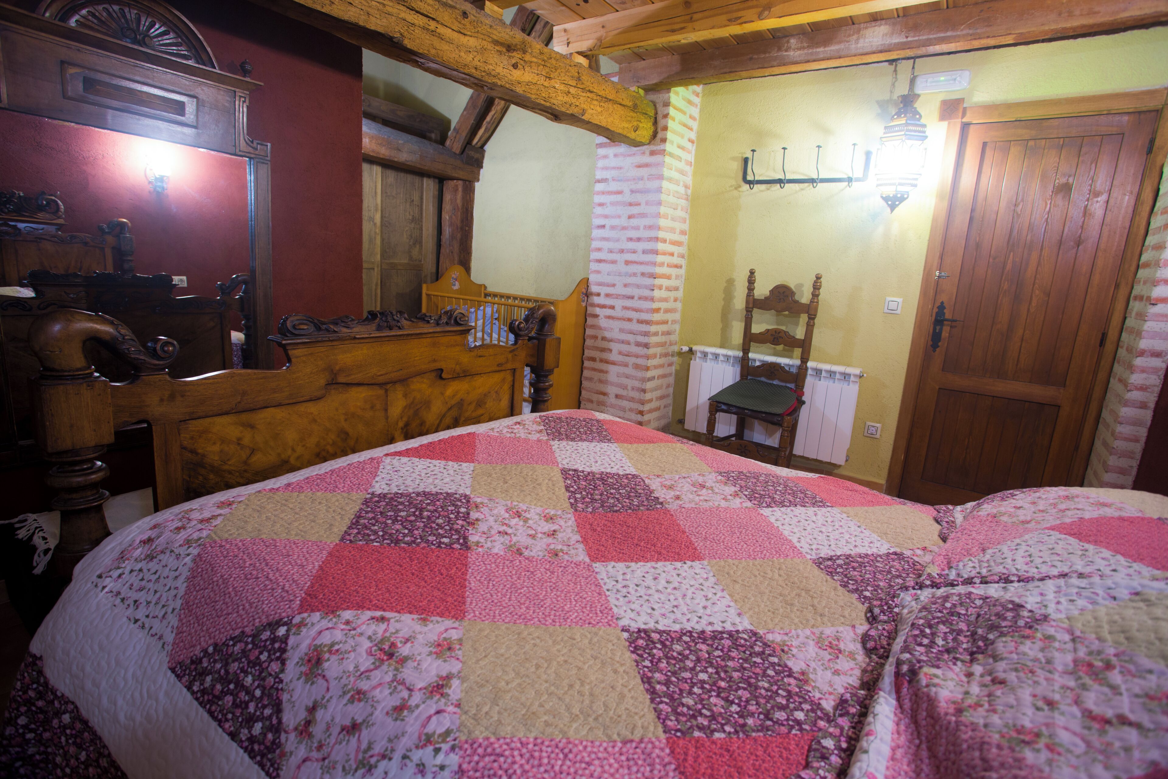 A bedroom with a wooden bed, a dresser, a mirror, and a door.