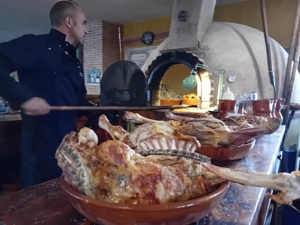 A chef preparing a large roasted bird in a kitchen with an oven and various cooking utensils.