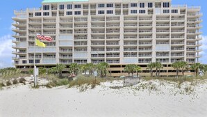 A multi-story hotel with balconies, located near a beach with palm trees. - Regency Isle 711  2 BR 2 5 BA  sleep 8  gulf-front (Orange Beach)