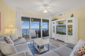 Un salon comprenant un canapé, une table basse et un meuble pour la télévision, un balcon avec vue et un ventilateur de plafond.