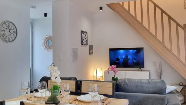 Un salon moderne comprenant un coin repas, un escalier et un téléviseur.