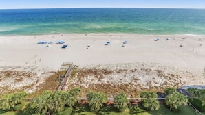 A beach with umbrellas, a lifeguard tower, and palm trees. - Regency Isle  Beachfront Bliss   Amazing Views  2 bedrooms (Orange Beach)