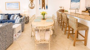 A dining area with a round table, chairs, and a chandelier. - Regency Isle  Beachfront Bliss   Amazing Views  2 bedrooms (Orange Beach)