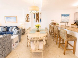 Uma sala de jantar com mesa redonda, cadeiras e um candelabro.