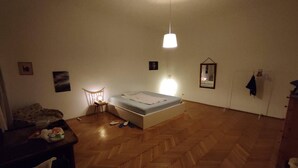 Une pièce comprenant un lit, une chaise, une petite table et un luminaire suspendu.