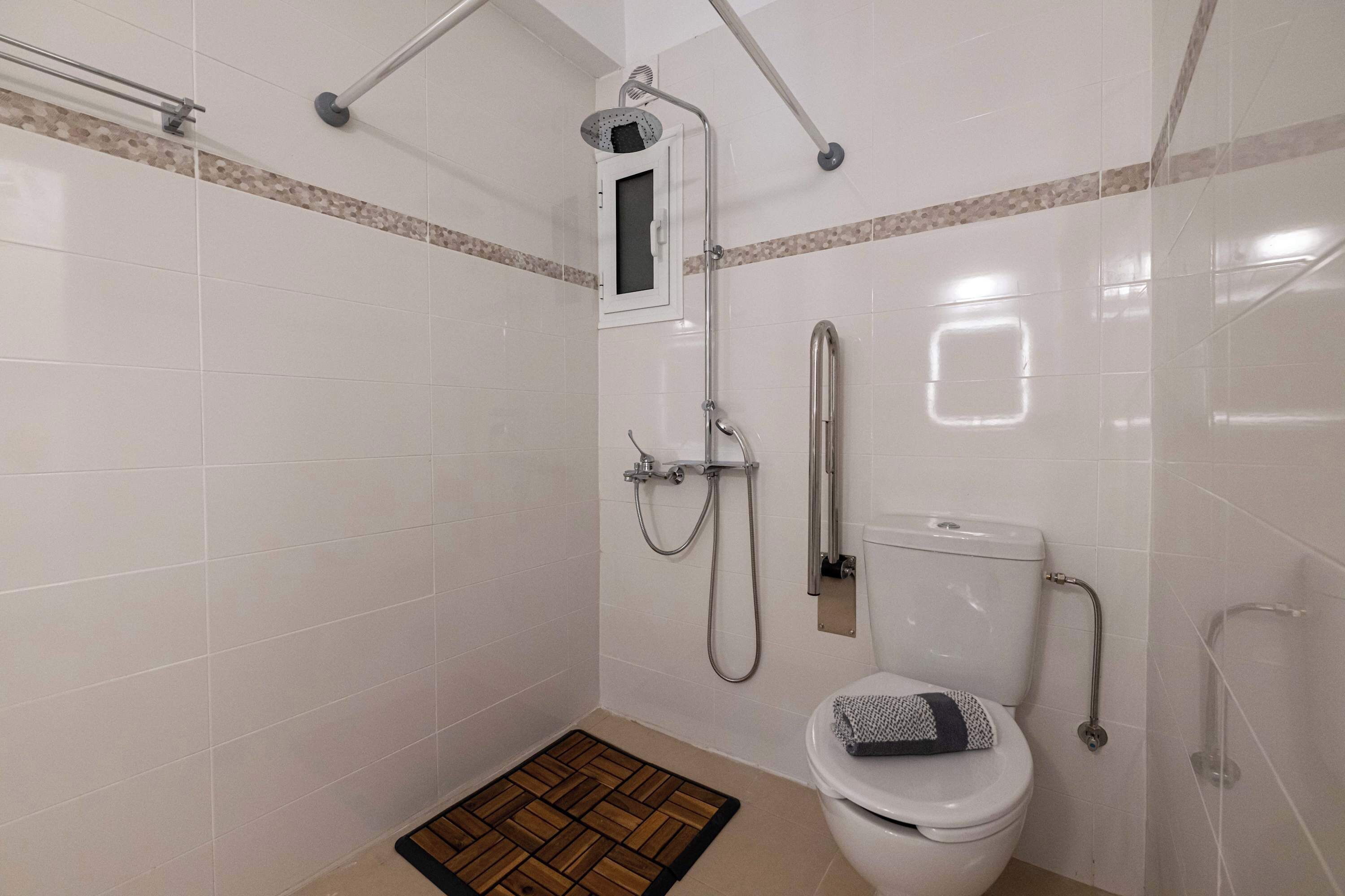 A bathroom with a shower, toilet, and grab bars.