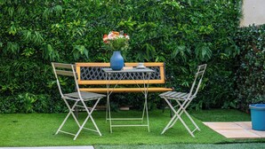 A small outdoor seating area with a bench and two chairs, a table, and a vase with flowers. - Home Easy Kalamata Central Getaway Priv Parking (Kalamata)