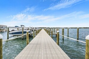 Een houten steiger die naar een aanlegsteiger met boten loopt, uitstukkend in het water.