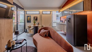 A modern kitchen with a built-in refrigerator, a dining area with a round table and chairs, and a sofa with patterned cushions. - NOK Comfortable 3BR Apartment in Gardens Bogota (Bogotá)