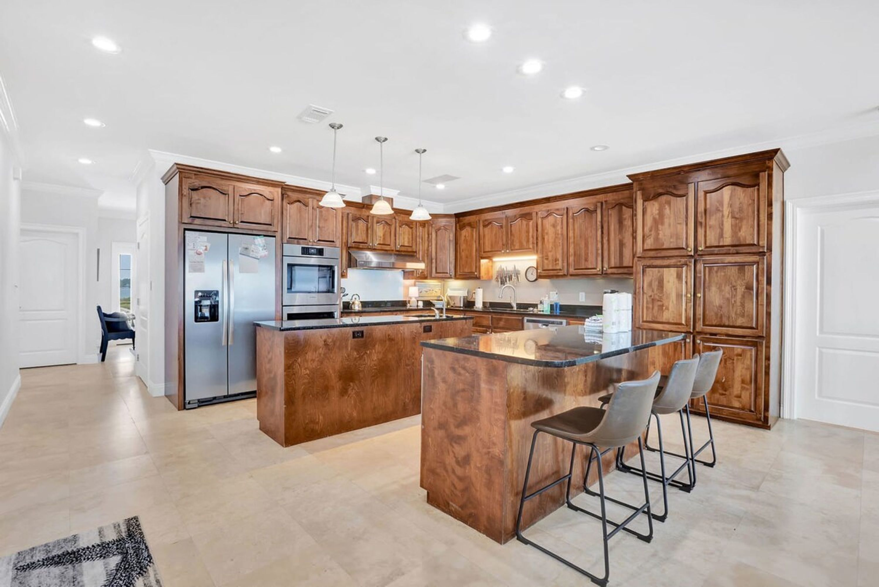 A modern kitchen with wooden cabinets, stainless steel appliances, and a central island with bar stools.