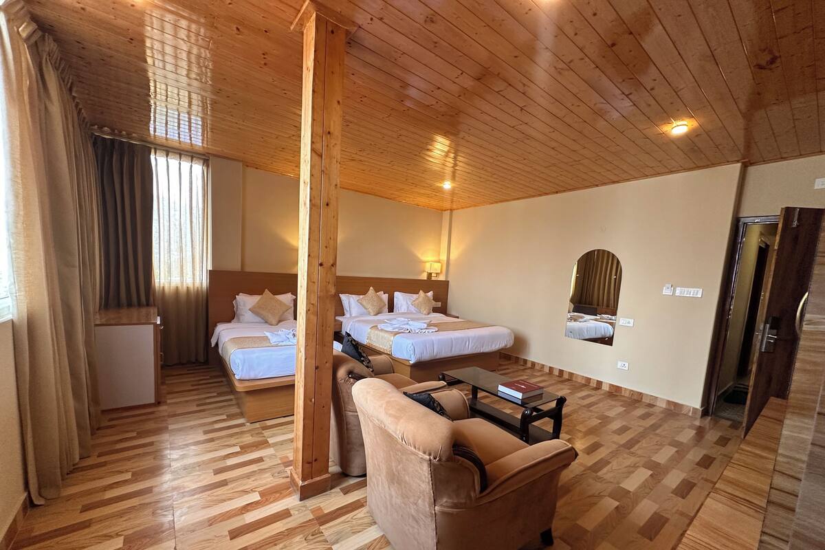 A hotel room with two beds, a sofa, a small table, and a mirror.