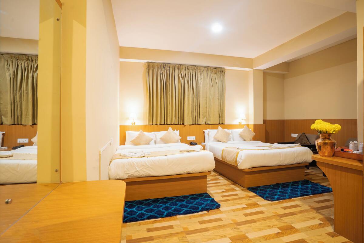 A hotel room with two beds, a wooden desk, and a small bathroom area.