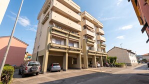 A multi-story residential building with balconies, parked cars, and a clear sky. - Bellissimo Appartamento Vicino al Centro (Sestri Levante)