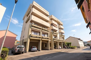 A multi-story residential building with balconies, parked cars, and a clear sky. - Bellissimo Appartamento Vicino al Centro (Sestri Levante)