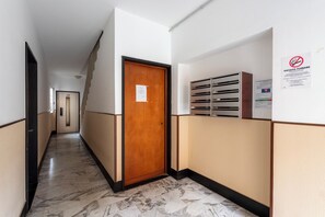 A hallway with a wooden door, a bulletin board with notices, and a tiled floor. - Bellissimo Appartamento Vicino al Centro (Sestri Levante)