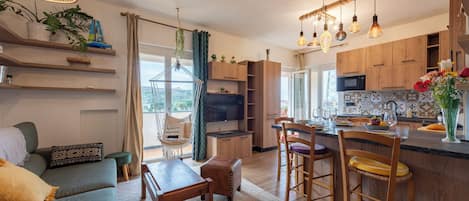 A modern kitchen with wooden cabinets, a dining area with a sofa and table, and a bar with stools.