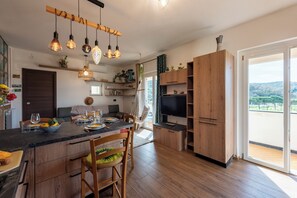 A modern kitchen with a wooden island, hanging pendant lights, and a large TV. - Bellissimo Appartamento Vicino al Centro (Sestri Levante)