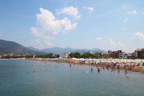 Una playa con sombrillas y gente nadando.