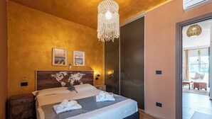 A bedroom with a bed, a wooden headboard, a world map, two wall-mounted lights, and a hanging light fixture. - Bellissimo Appartamento Vicino al Centro (Sestri Levante)