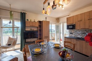 Una cocina moderna con armarios de madera, una mesa de comedor para cuatro personas y un sillón colgante junto a un ventanal grande.