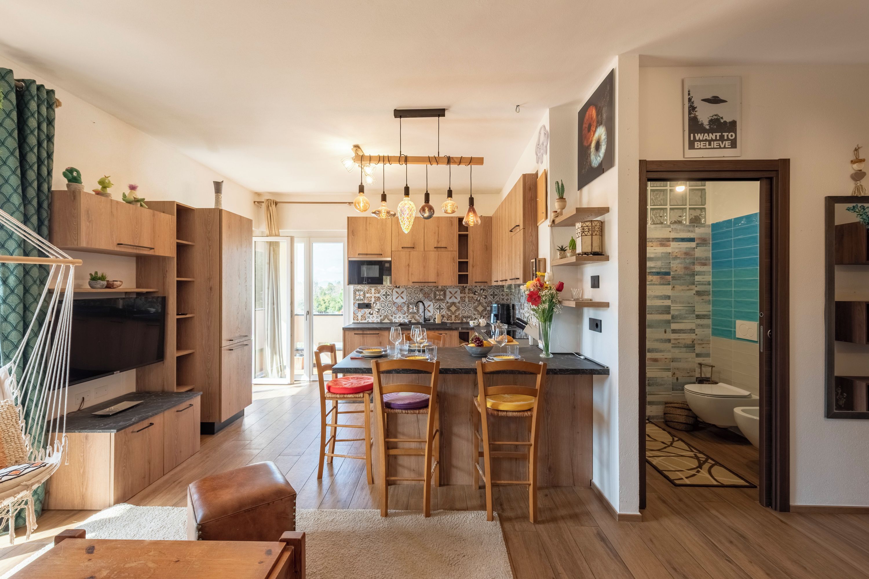 Una cocina moderna con armarios de madera, una isla central, taburetes de bar e iluminación colgante.
