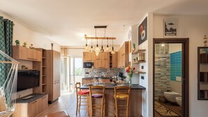A modern kitchen with wooden cabinets, a central island, bar stools, and pendant lighting. - Bellissimo Appartamento Vicino al Centro (Sestri Levante)