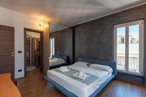 Un dormitorio moderno con una cama grande, un vestidor, un baño con ducha de vidrio y un balcón con vistas.