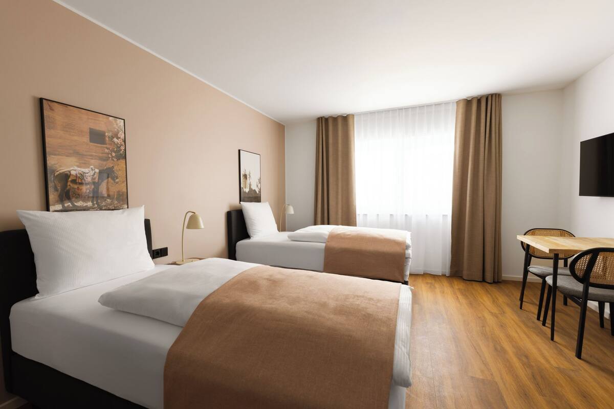 Ein Hotelzimmer mit zwei Betten, einem Schreibtisch und einem Stuhl.