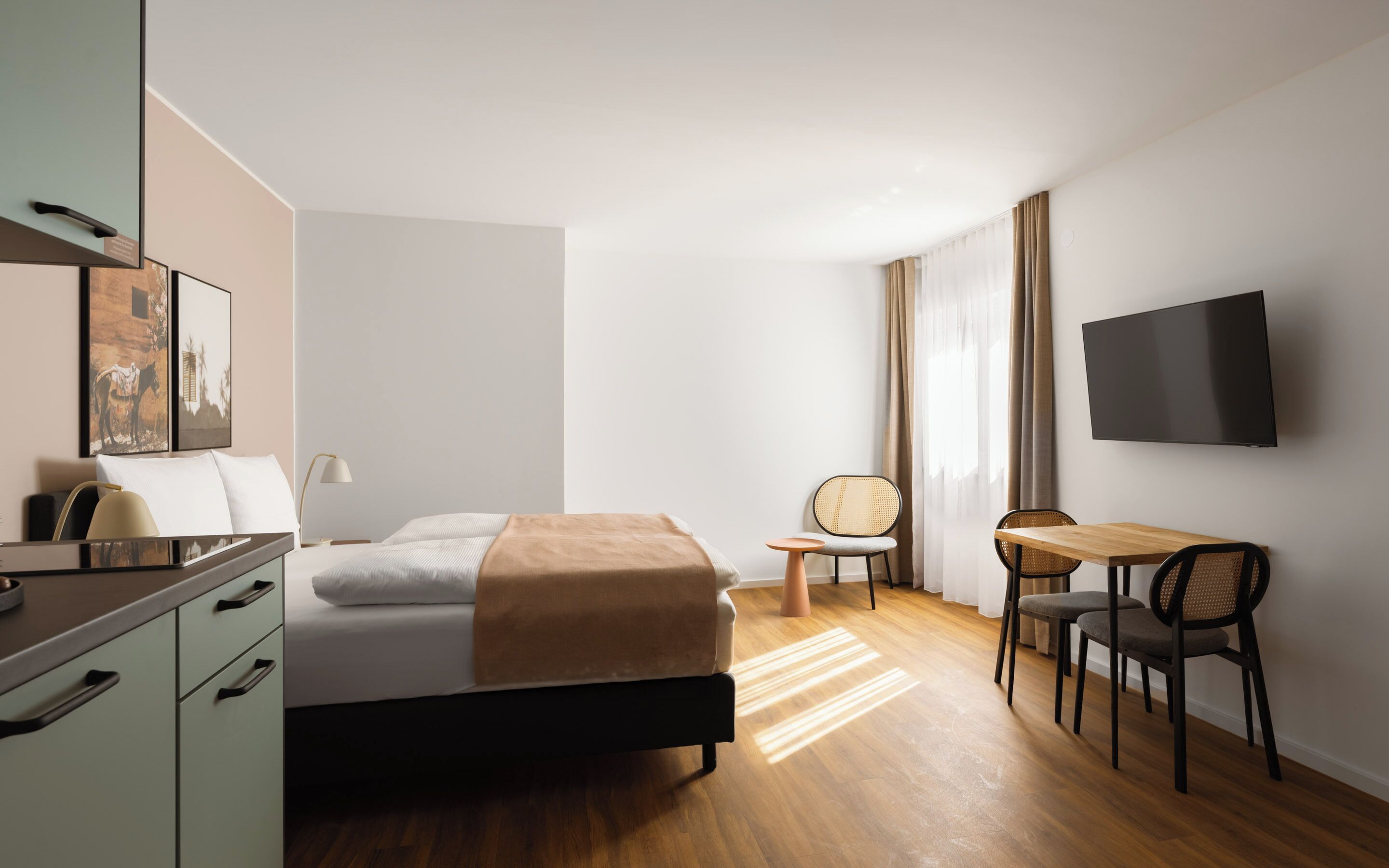 Una habitació d'hotel moderna amb un llit, una taula de treball, una cadira, un televisor i un armari.
