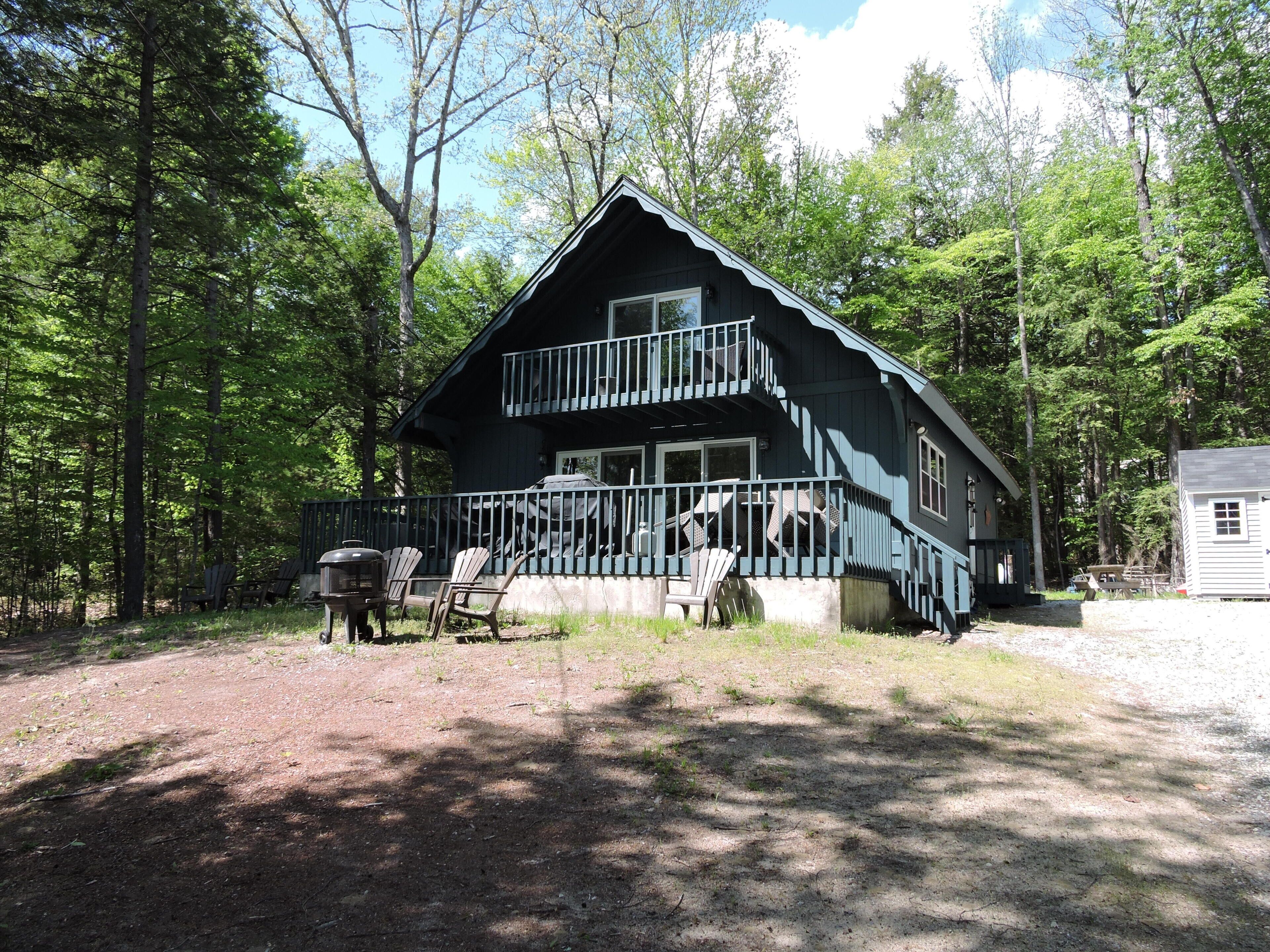 Une cabane dotée d’un balcon, entourée d’arbres.