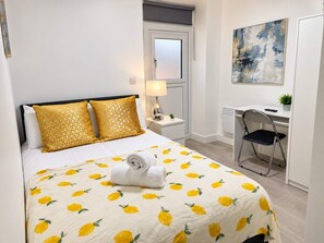 Une chambre d’hôtel avec un lit, un bureau, une chaise, une lampe et un tableau au mur.