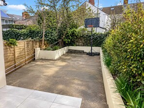 Un jardin avec un panier de basket, une clôture en bois et un espace dédié à la plantation.