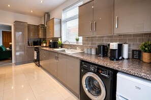 A modern kitchen with stainless steel appliances, a built-in dishwasher, and a coffee maker.