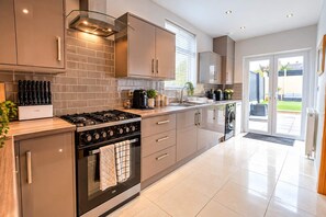 A modern kitchen with a gas stove, oven, and dishwasher, featuring a clean, minimalist design and ample natural light.