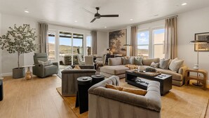 A spacious living room with a ceiling fan, large windows, and a view of the desert. - Isle Be Back: Private Hot Tub + Rec Center Passes! (Washington)