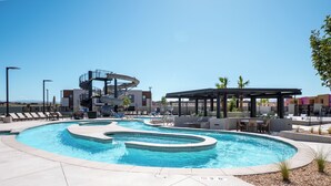 A swimming pool with a spiral slide, lounge chairs, and a covered seating area. - Isle Be Back: Private Hot Tub + Rec Center Passes! (Washington)