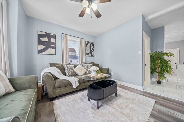 A living room with a sofa, a coffee table, and a ceiling fan.