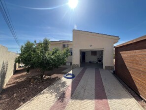 A residential property with a paved driveway, a small tree, and a garage door.