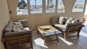 A room with two sofas, a small table, and a window with a view of the street.