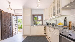 A modern kitchen with white cabinets, a granite countertop, and a built-in oven. - Lavender House - Hacienda 37 by Casasol (Nerja)